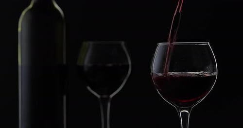 Pouring Red Wine into Glass on Black Background