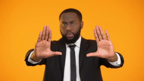 Man Gesturing Stop with Both Hands, Orange Background