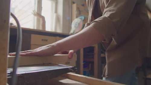 Man Cutting Wood in Workshop with Machine