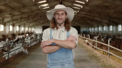 Young Man in Working Uniform Standing at Farm with Goats