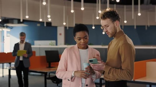 Handsome Office Worker Showing Something to His Female Coworker at the Smartphone