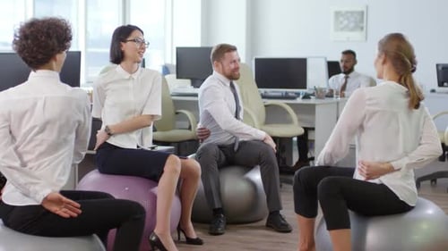 Employees Stretch on Exercise Balls in Modern Office
