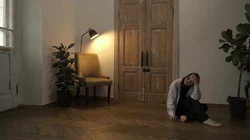 Woman Sitting Barefoot on Hardwood Floor in Empty Room