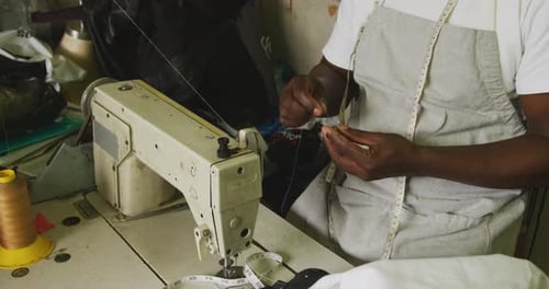 Afrikanischer Mann bereitet den Faden zum Nähen vor