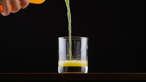 Mann gießt Orangensaft-Soda in Zeitlupe in Glas