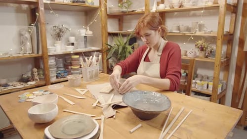 Young Female Pottery Artist Shaping Edge of Wet Clay Bowl in Studio