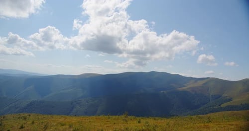 Rolling Hills and Mountains Under a Cloudy Sky