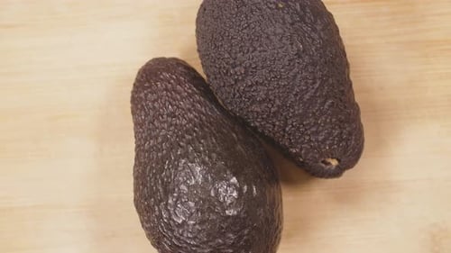 Two Fresh Dark Avocados on a Cutting Board