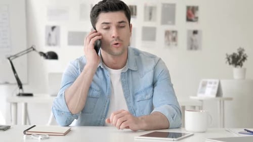 Man Talking on Phone at Desk in Office