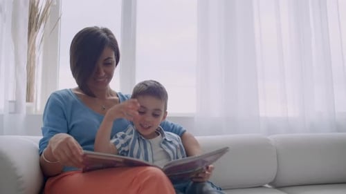 Mother and Child Reading Together on White Couch