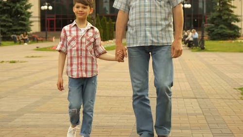 Boy and Senior Man Walking Hand-in-Hand