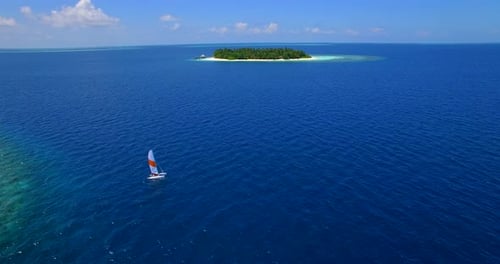 Aerial drone view of a man and woman sailing on a boat to a tropical island