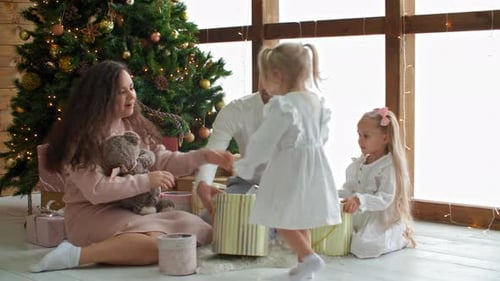 Happy Parents Looking at Adorable Daughters Enjoying Xmas Gifts
