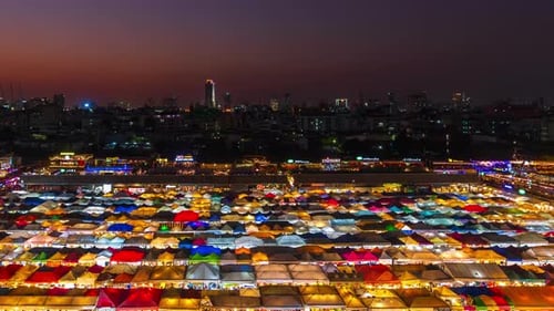 day to night time lapse of Train Night Market Ratchada (Talad Rot Fai) at night in Bangkok, Thailand