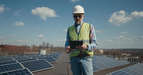 Engineer Using Tablet Between Solar Panels