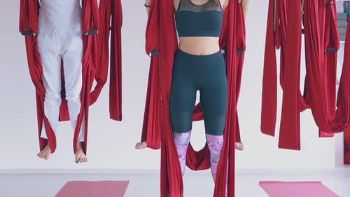 Young Adults Participate in Aerial Yoga Class