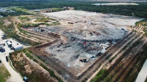 Dépotoir d'une grande ville avec des bulldozers et des camions à ordures qui déchargent les déchets vers une décharge