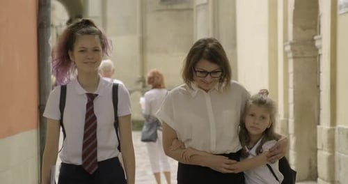 Madre y dos hijas estudiantes caminando juntas