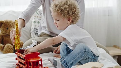 Child Playing with Toys on Bed with Woman