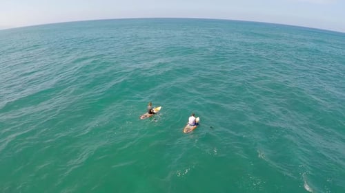 Aerial view of a man sitting while sup stand-up paddleboard surfing in Hawaii.