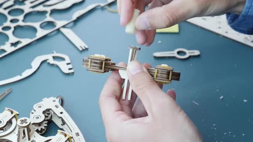 Homme assemblant un jouet de puzzle mécanique en bois. Gros plan de mains masculines tenant de petits détails du jouet