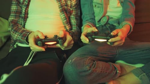 Hands of a Man and Girl Holding a Joysticks to Play Video Games on TV