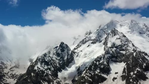 Air Flight Through Mountain Clouds Over Beautiful Snowcapped Peaks of Mountains and Glaciers