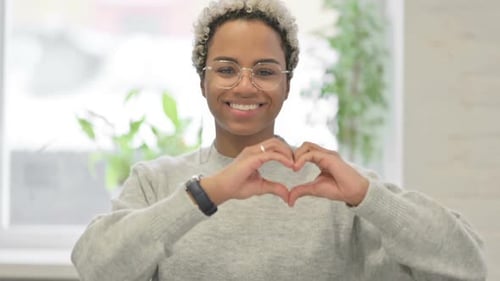 Smiling Woman Makes Heart Shape with Hands