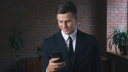 Smiling Businessman Using Smartphone in Office Setting