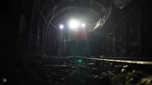 Slow Motion Workers with helmets and equipment walking in chrome mine tunnel