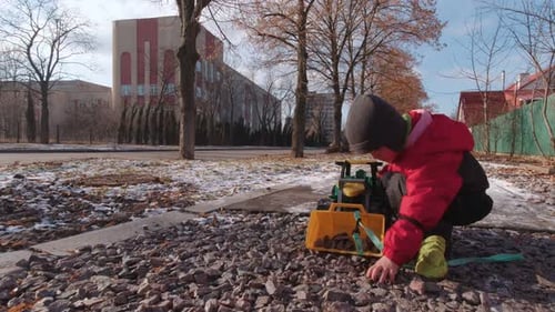Young Child Playing with a Toy Tractor Outdoors