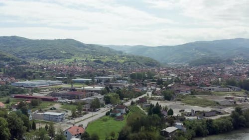 Drone is a Video of City That is Surrounded By Mountains with Forests and Peaks