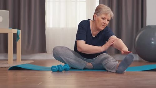 Senior Woman Stretching on a Yoga Mat Indoors