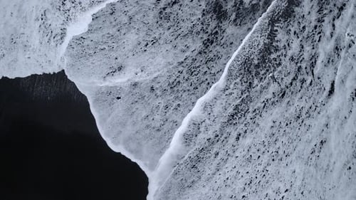 Waves Crashing on Black Sand Beach from Above