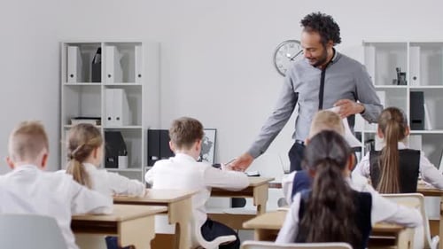 Teacher Distributing Papers to Elementary School Children