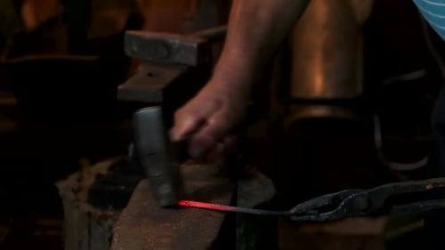 Blacksmith Strikes Red Hot Metal with Hammer