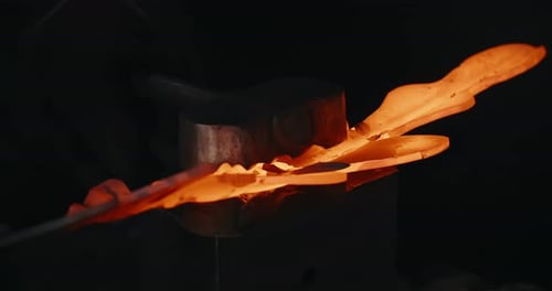 Blacksmith Forging Hot Metal in Dark Workshop