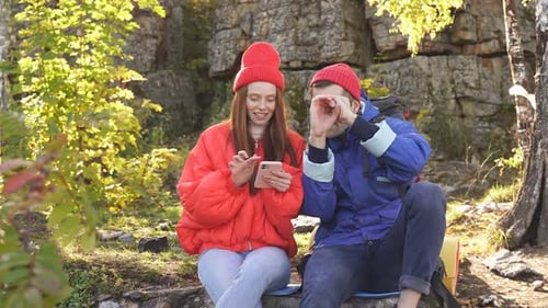 Young Couple Relaxing Outdoors with Mobile Phone