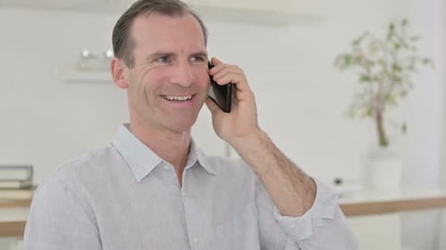 Adult Man Smiling and Talking on Smartphone Indoors