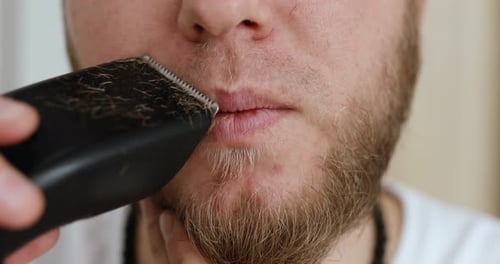 Man Trimming Beard with Electric Razor Close Up