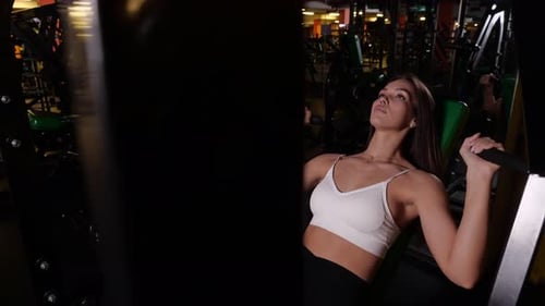 Young Woman Using Arm Exercise Machine at Gym