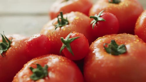 Video of close up of fresh tomatoes and cherry tomatoes over wooden background