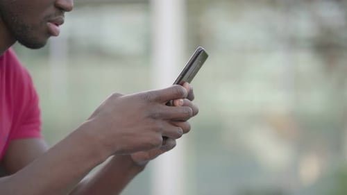 Closeup of Young Male Hands Typing on Smartphone in Park
