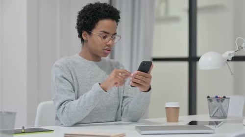 Young Woman Using Smartphone at Desk Indoors