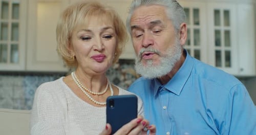 Senior Couple Using Phone Together Indoors