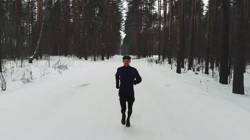 Athletic Man Running Through Snowy Winter Forest