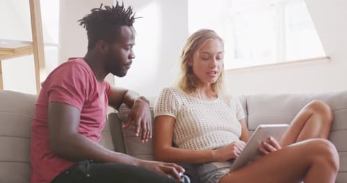 Couple Relaxing on Sofa with Tablet Indoors