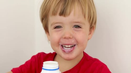 Happy Child Eating Yogurt or Milk Close Up
