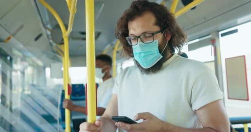 Man Rides Bus Using Smartphone Wearing Mask