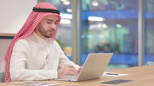 Young Adult Typing on Laptop in an Office